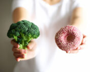 woman holding broccoli and donut