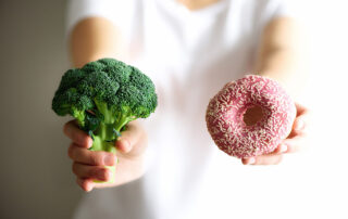 woman holding broccoli and donut