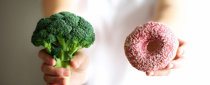 woman holding broccoli and donut